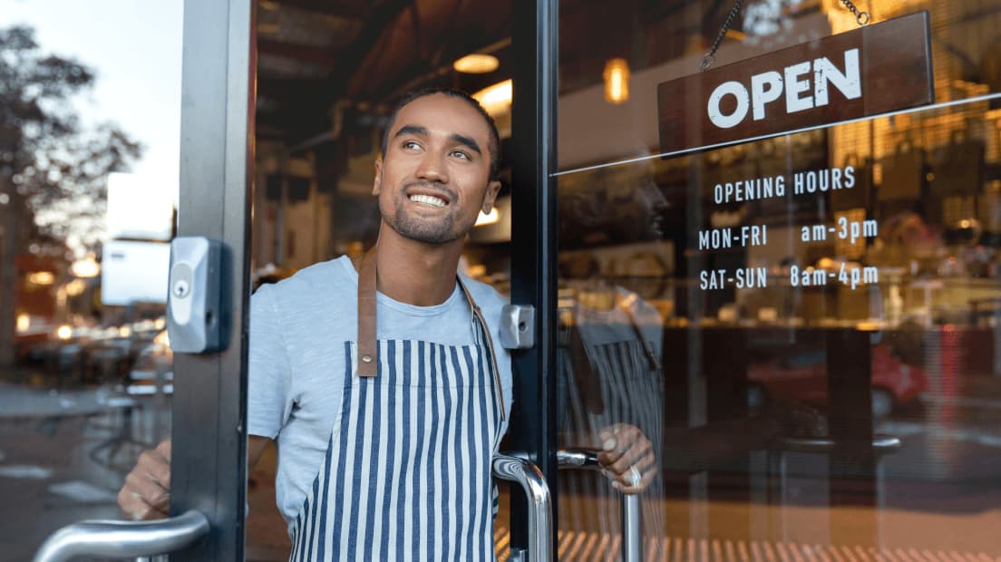 Cafe worker looking out through open door smiling